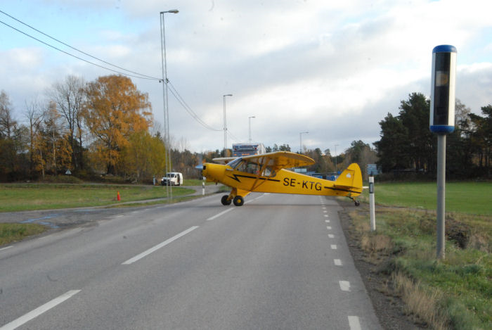 Piper PA18, Super Cub, SE-KTG.Notera hastighetskameran vid sidan av vägen. Någon hastighetsöverträdelse lär det dock inte vara i detta fallet. Foto: Bengt Simson.