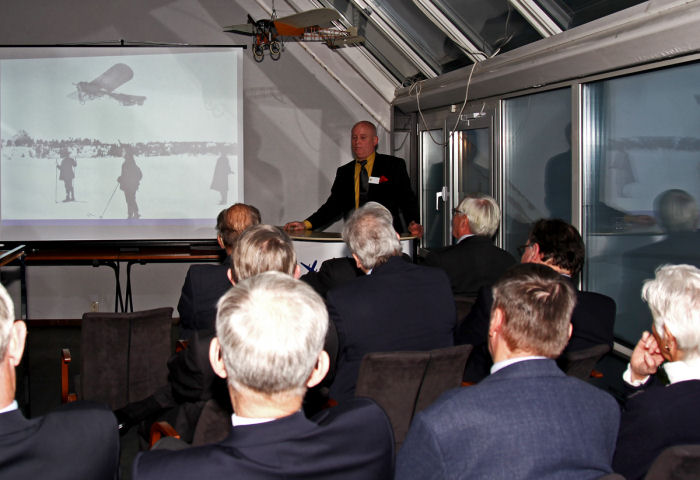 Mikael Carlson berättar för publiken om hur det var att flyga dåtidens flygplan. I taket hänger en av  Mats Johanssons Blériot-modeller. Foto: Gunnar Åkerberg