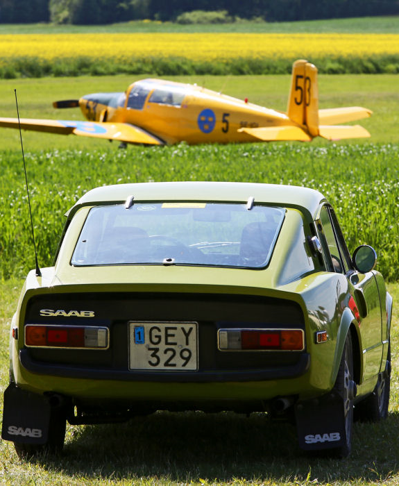 Två Saabklassiker på grönbete, Saab 97 Sonett III och i bakgrunden Saab 91B Safir. Foto: Gunnar Åkerberg