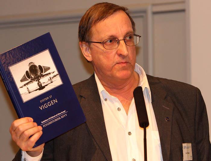 Bernt Olsson visar upp 2009 års flyghistoriska Revy som har titeln System 37 Viggen och är sammanställd av SFF ordförande Ulf Edlund och Hans Kampf. En fantastiskt intressant och fin bok på 223 sidor och mängder med bilder. Boken är inbunden med hårda pärmar och ingår i medlemsavgiften i SFF. Foto: Gunnar Åkerberg.